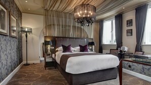 A large bed with a headboard, a floor lamp, and a table with books and a glass of wine. - Ivy Hill Hotel, BW Signature Collection (Ingatestone)