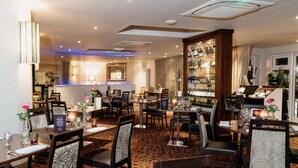 A restaurant with multiple dining tables and chairs, a wine rack, and a bar area. - Ivy Hill Hotel, BW Signature Collection (Ingatestone)