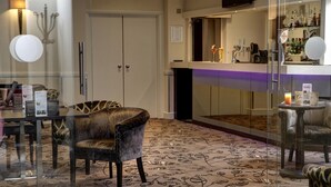 A hotel lobby with a glass partition, a bar area with a purple-lit counter, and a patterned carpet. - Ivy Hill Hotel, BW Signature Collection (Ingatestone)
