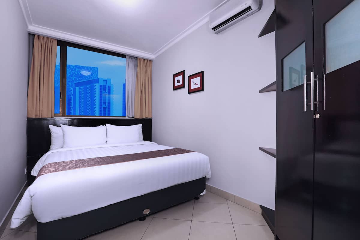 A hotel room with a bed, a wardrobe, and a window with curtains.