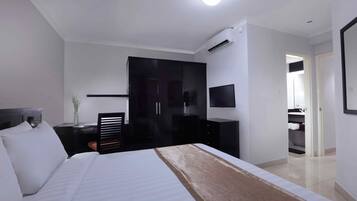 A hotel room with a large bed, a desk, a wardrobe, and a TV.