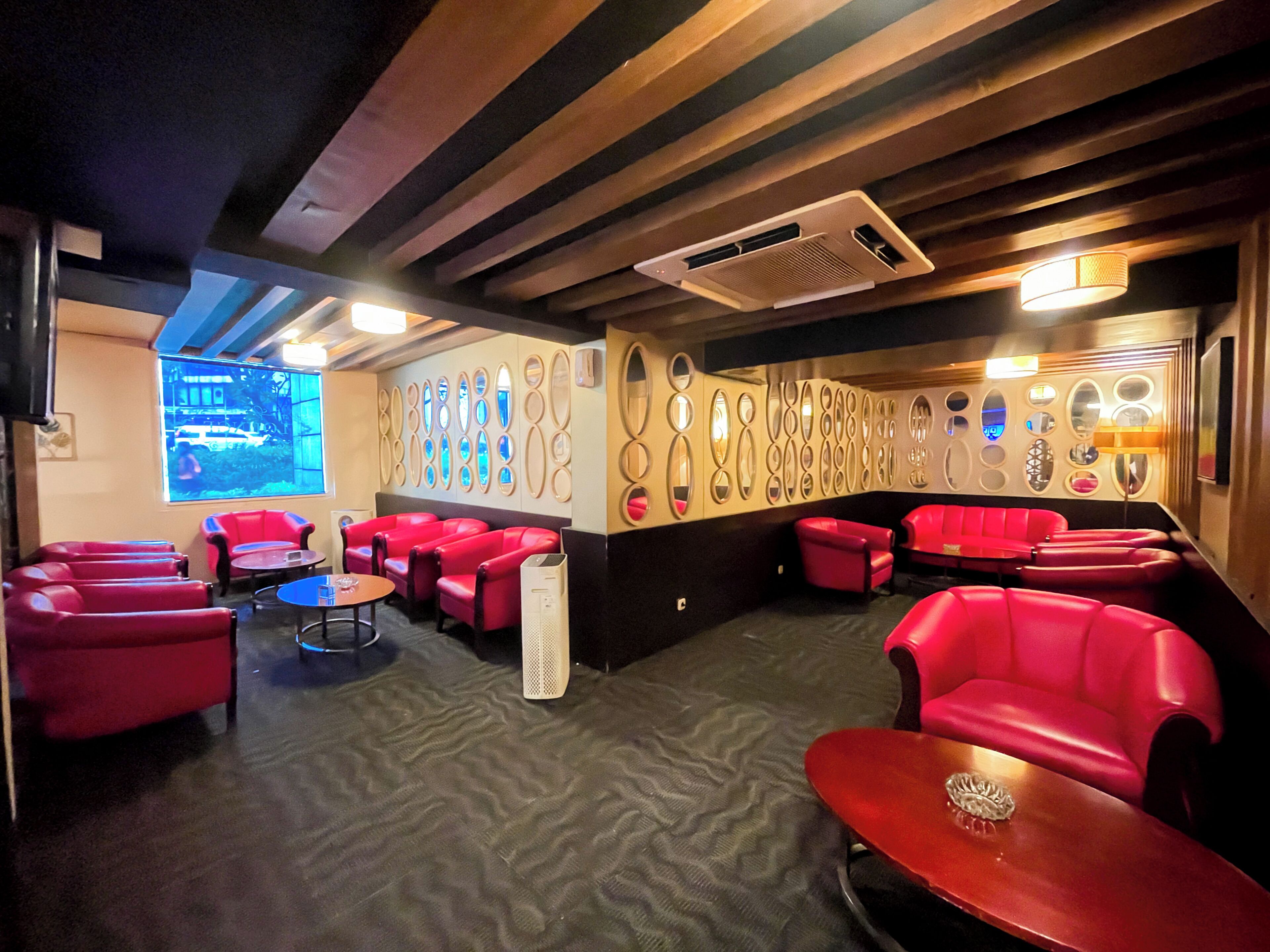 A room with red seating, a patterned wall, and a window with a view.