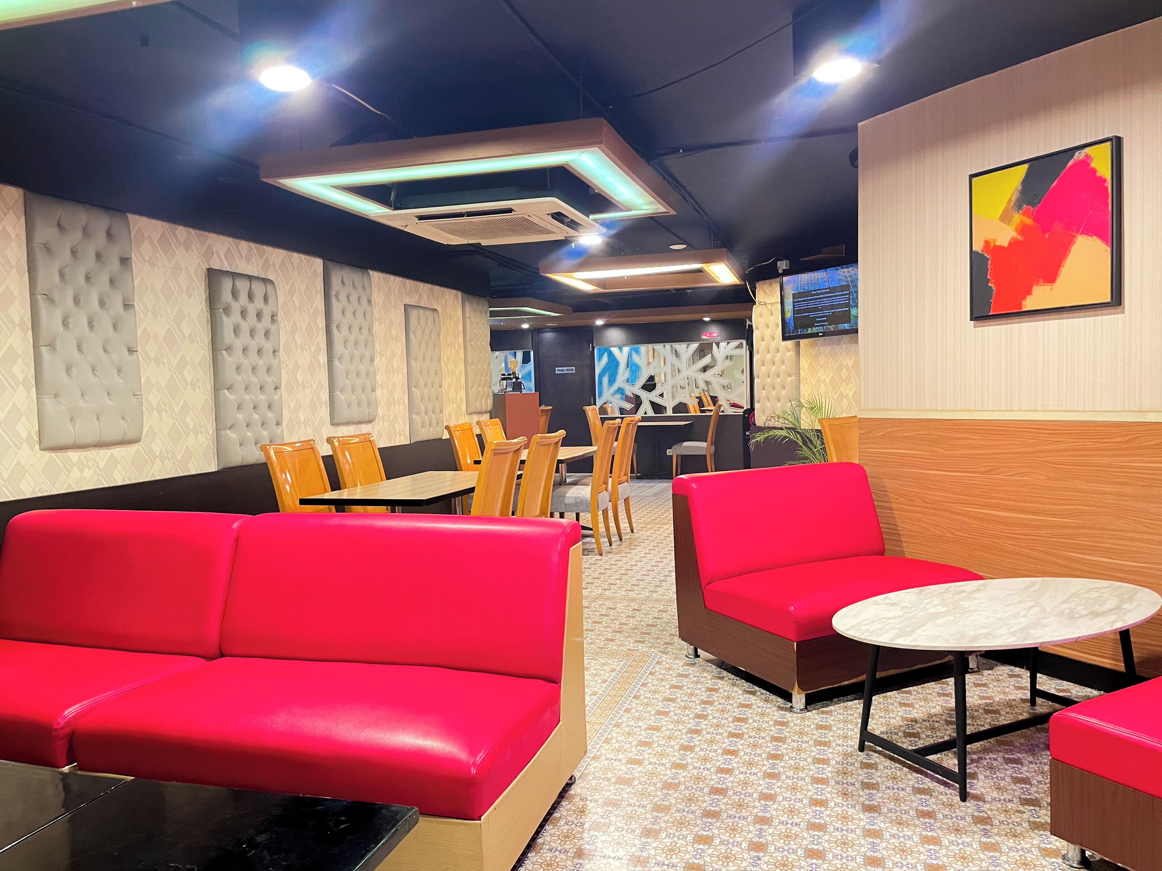 A restaurant interior with red seating, a wooden counter, and a tiled floor.