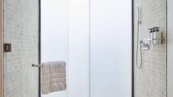 A modern bathroom with a glass door, a shower, and a towel hanging on the door handle.