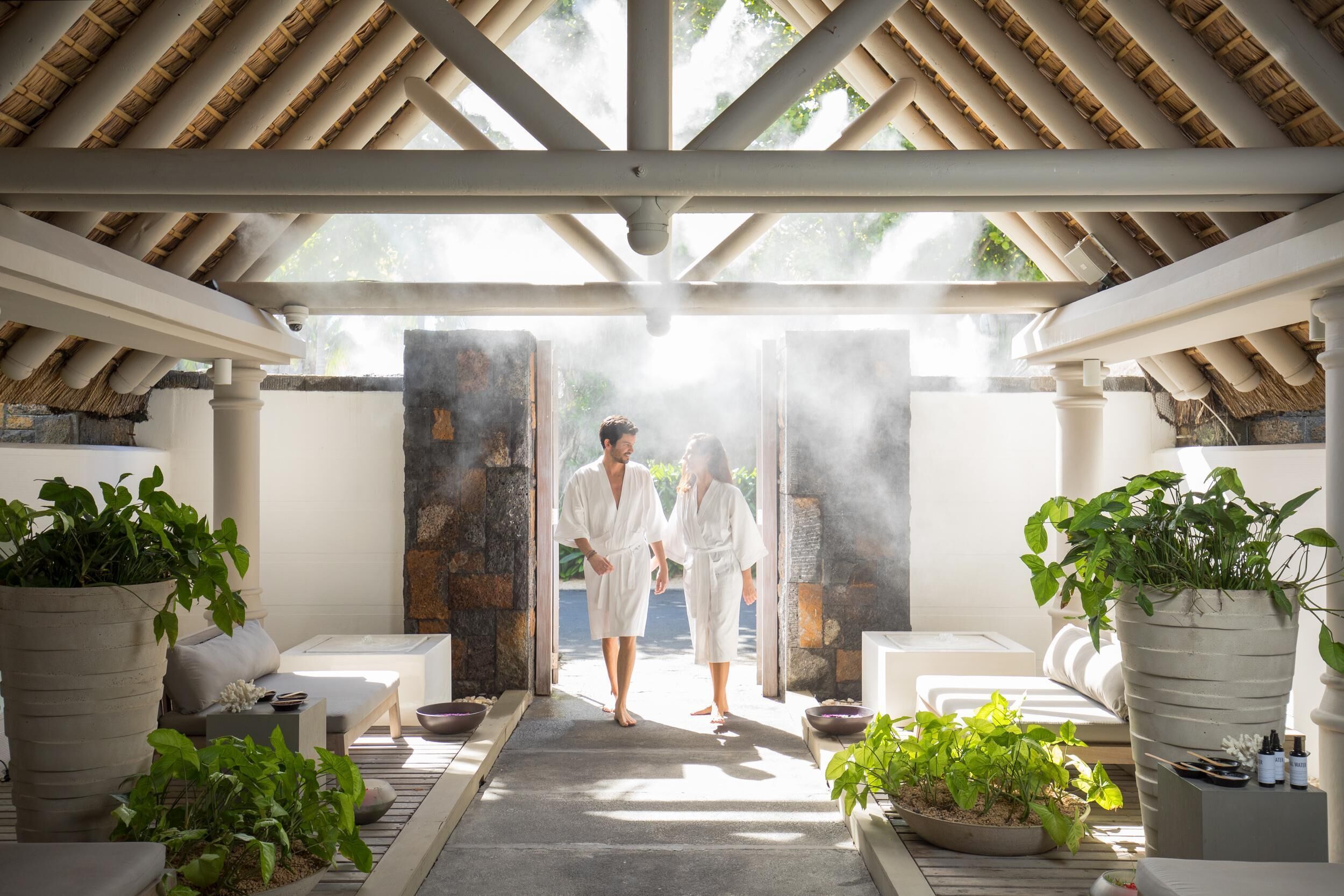 A spa area with a thatched roof, stone walls, and potted plants.