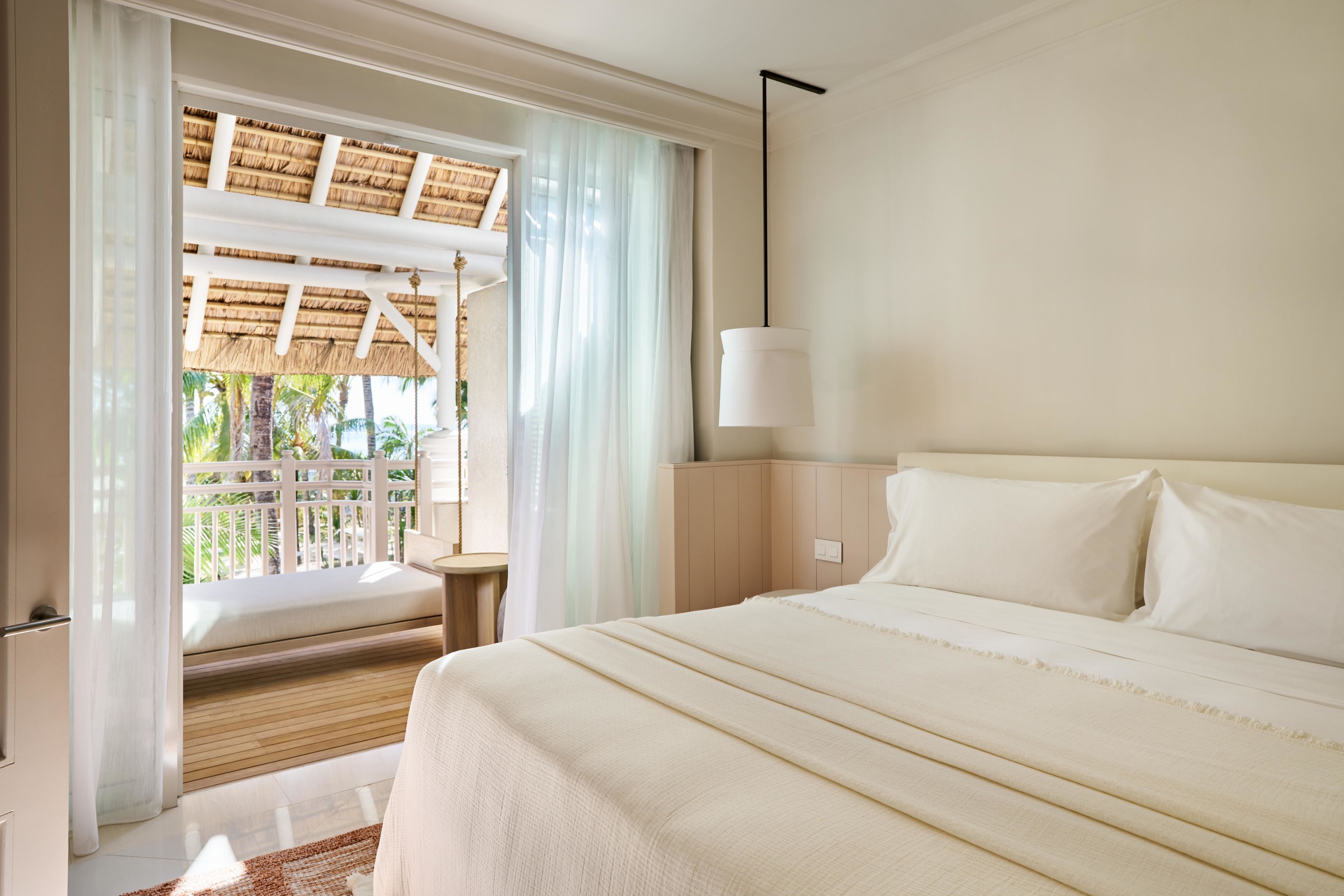 Une chambre d’hôtel avec un lit, une table de chevet, une lampe, une fenêtre avec des rideaux et une vue sur l’extérieur.
