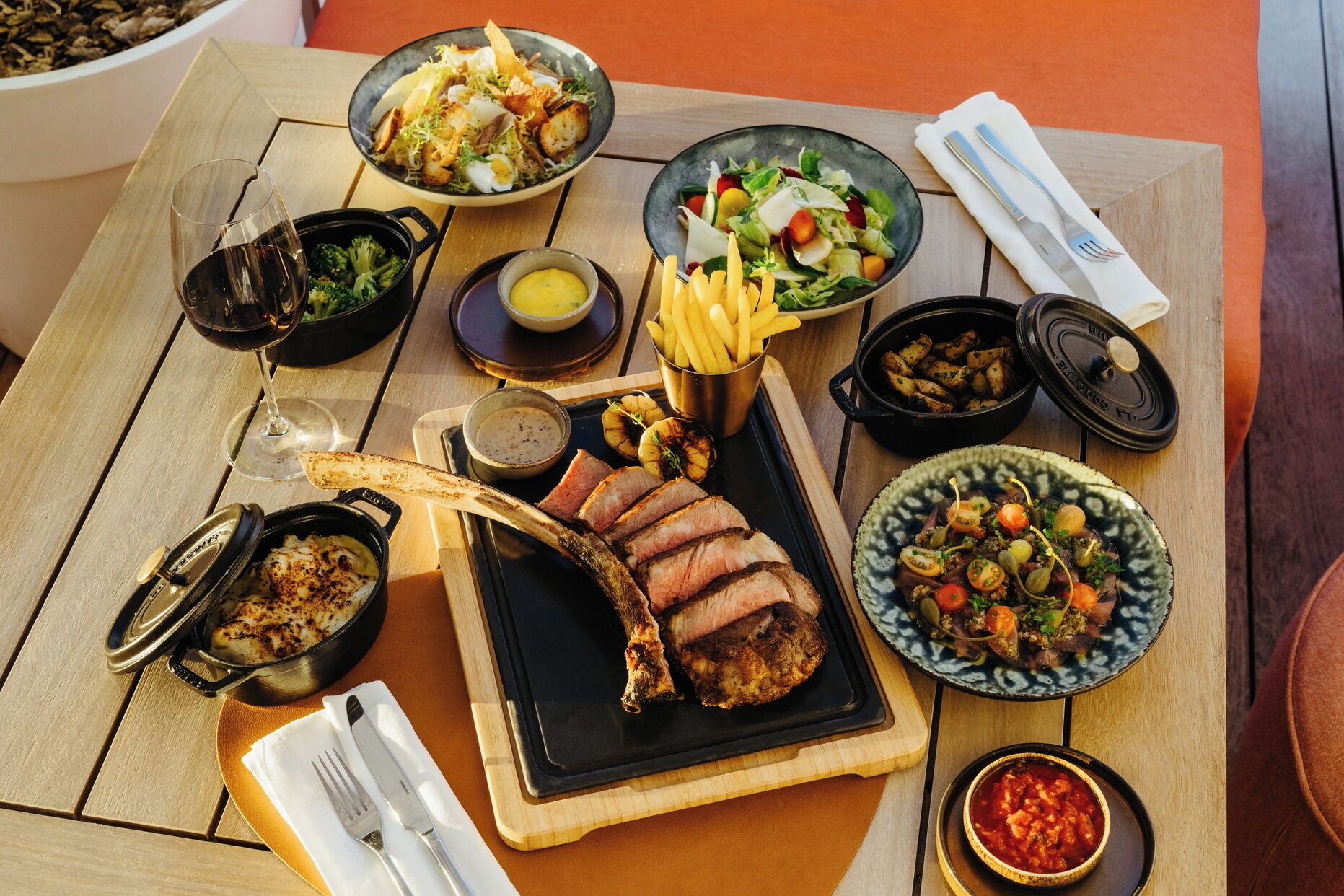 Una mesa dispuesta con diversos platos, incluyendo un bistec, ensaladas y acompañamientos.