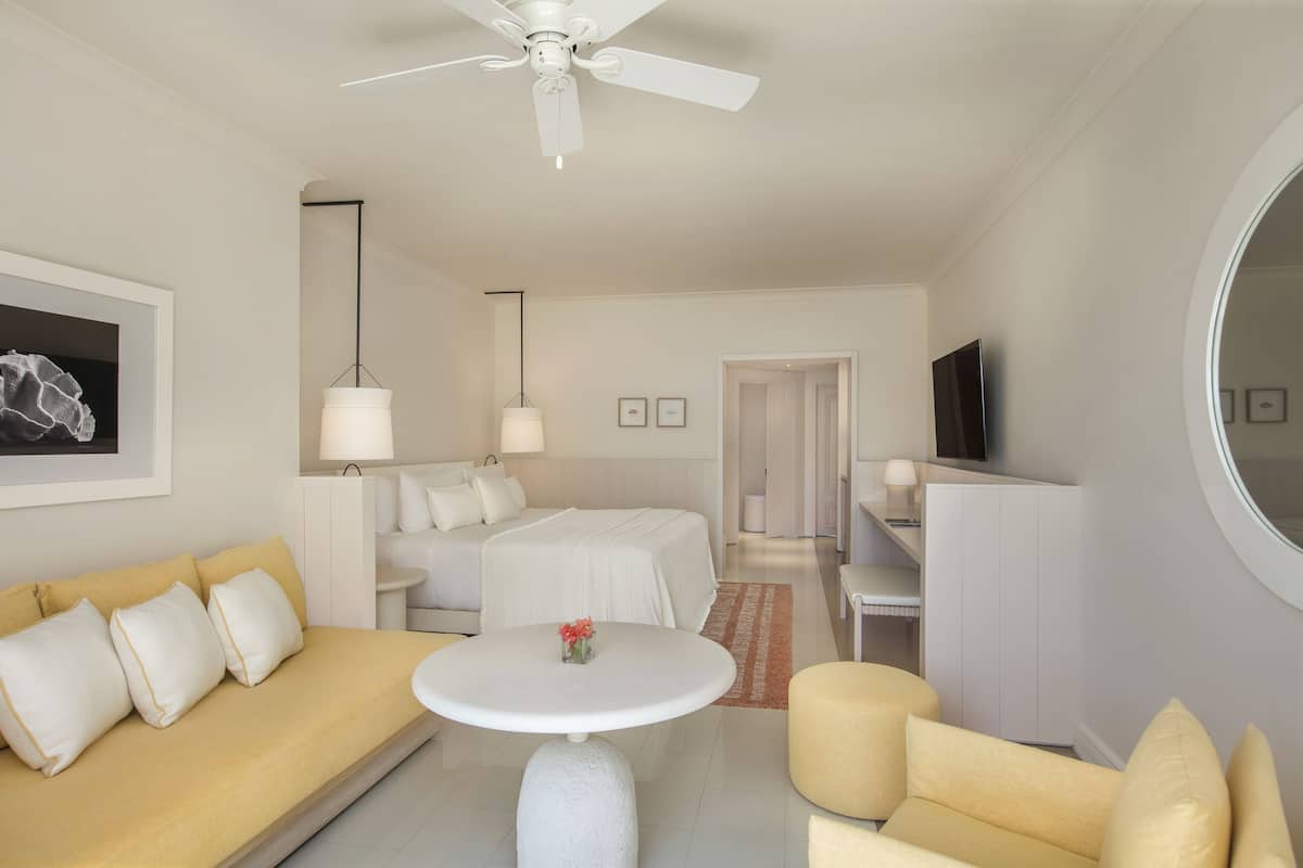 Habitació d'hotel moderna amb llit, sofà, taula rodona i televisió.