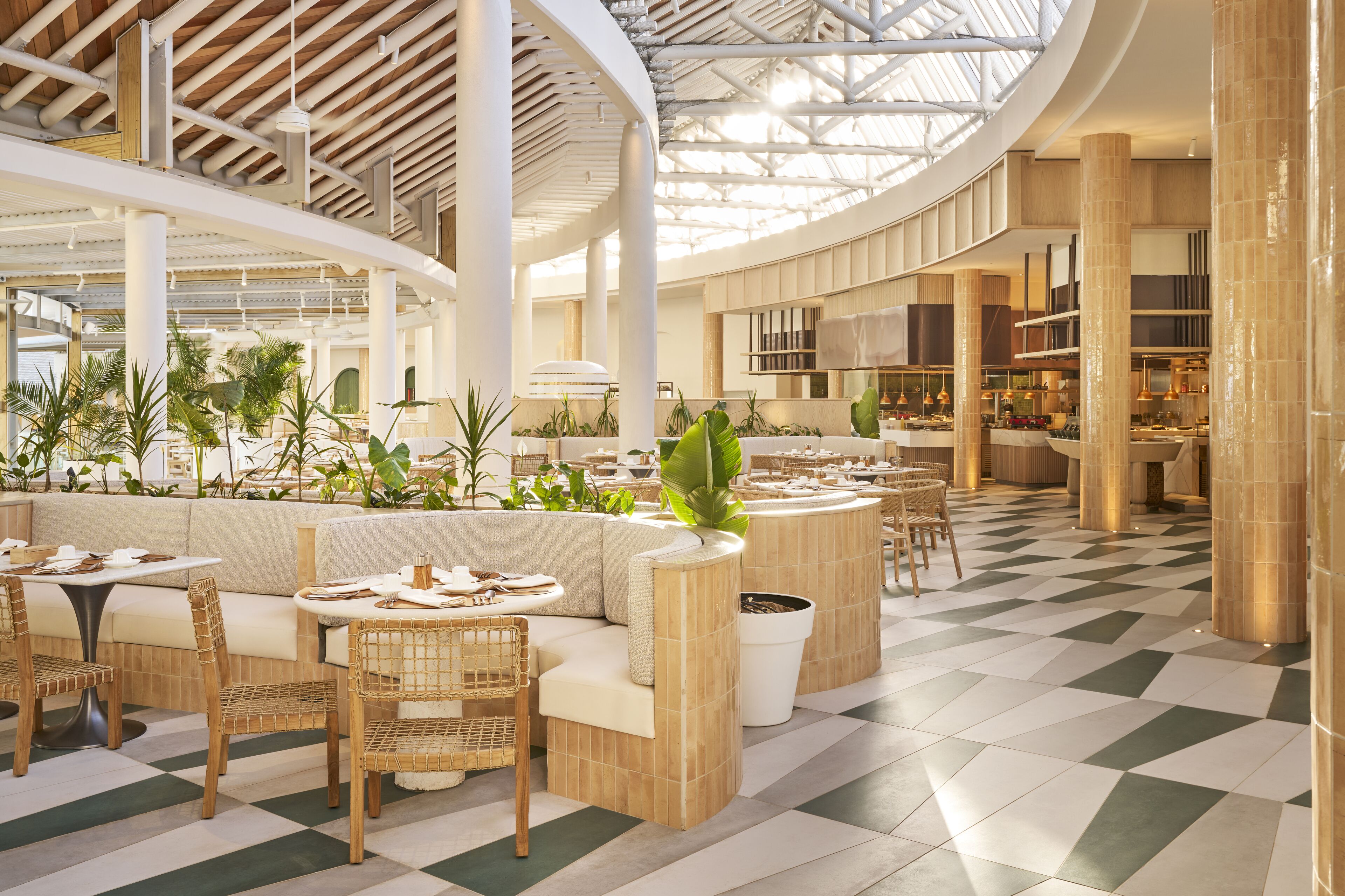 A spacious indoor area with seating arrangements, a checkered floor, and a high ceiling with natural light.