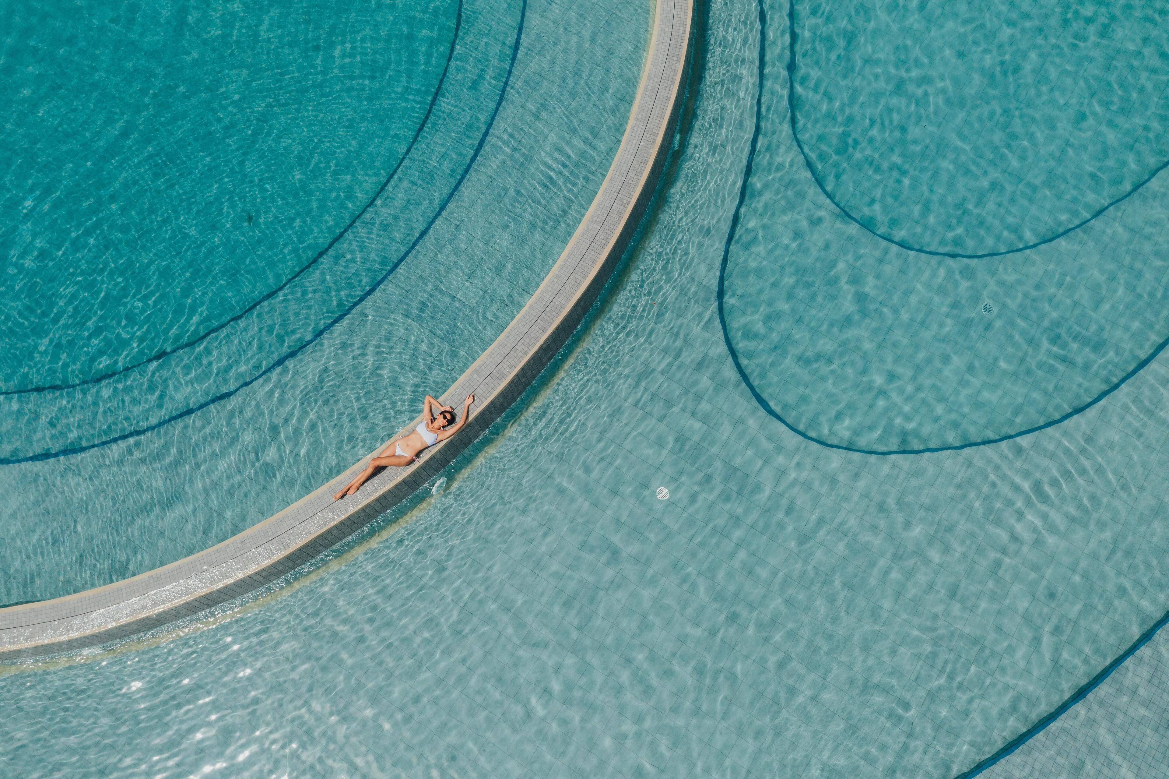 An aerial view of a swimming pool with clear water and a curved edge.