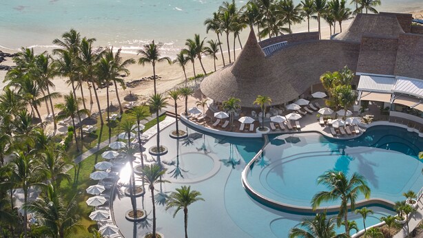 Un resort con una gran piscina, palmeras y una playa.