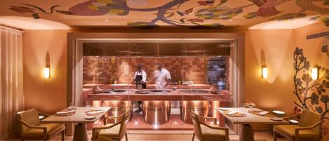 A restaurant with a central bar, tables with chairs, and a decorative ceiling.