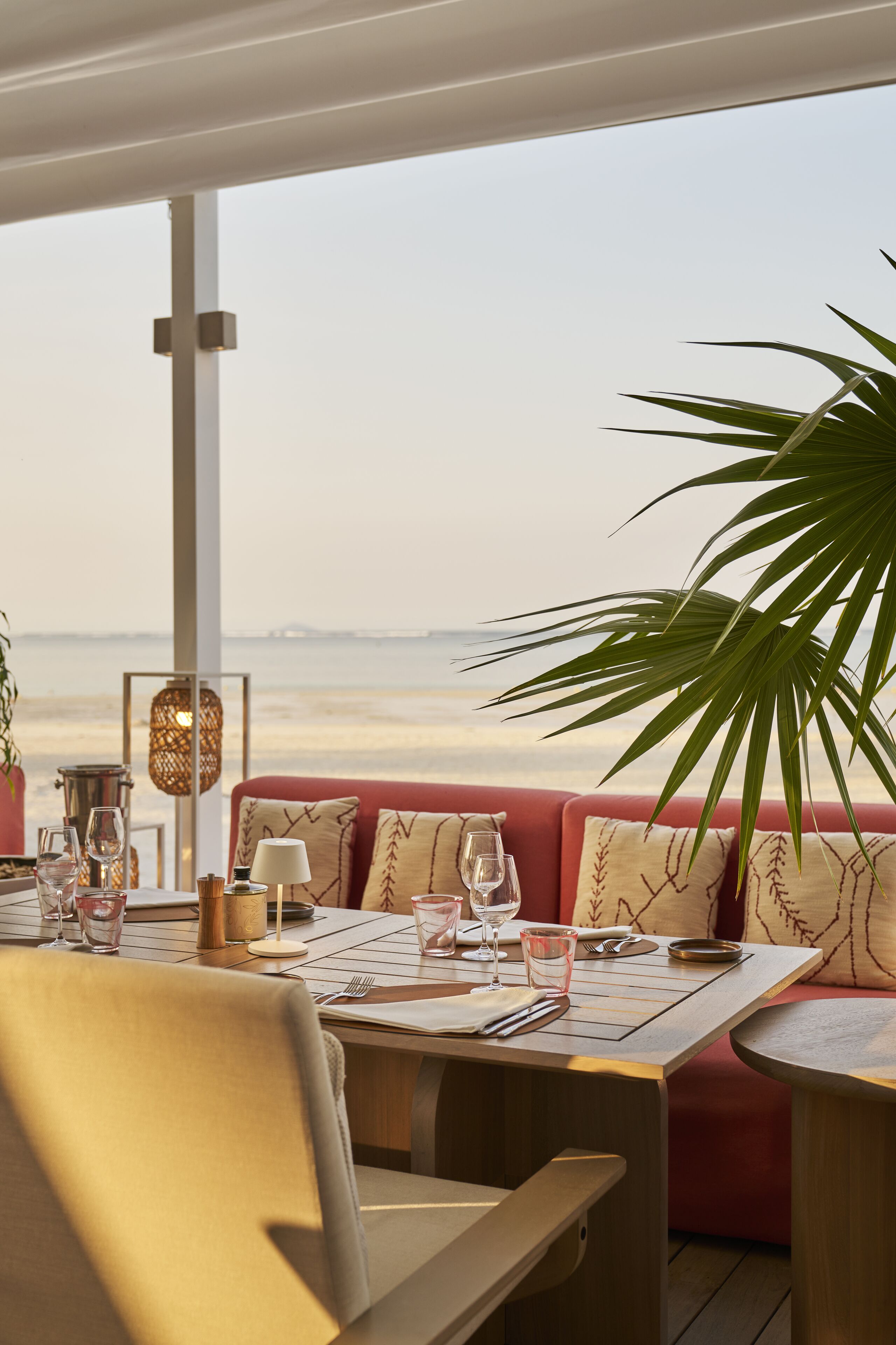A dining area with a table set for two, overlooking a beach.