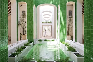A corridor with a central water feature, white seating areas, and green-tiled walls. - LUX* Belle Mare (Belle Mare)