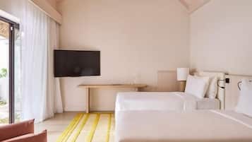 Habitación de hotel con dos camas, televisión, escritorio y ventana con cortinas.