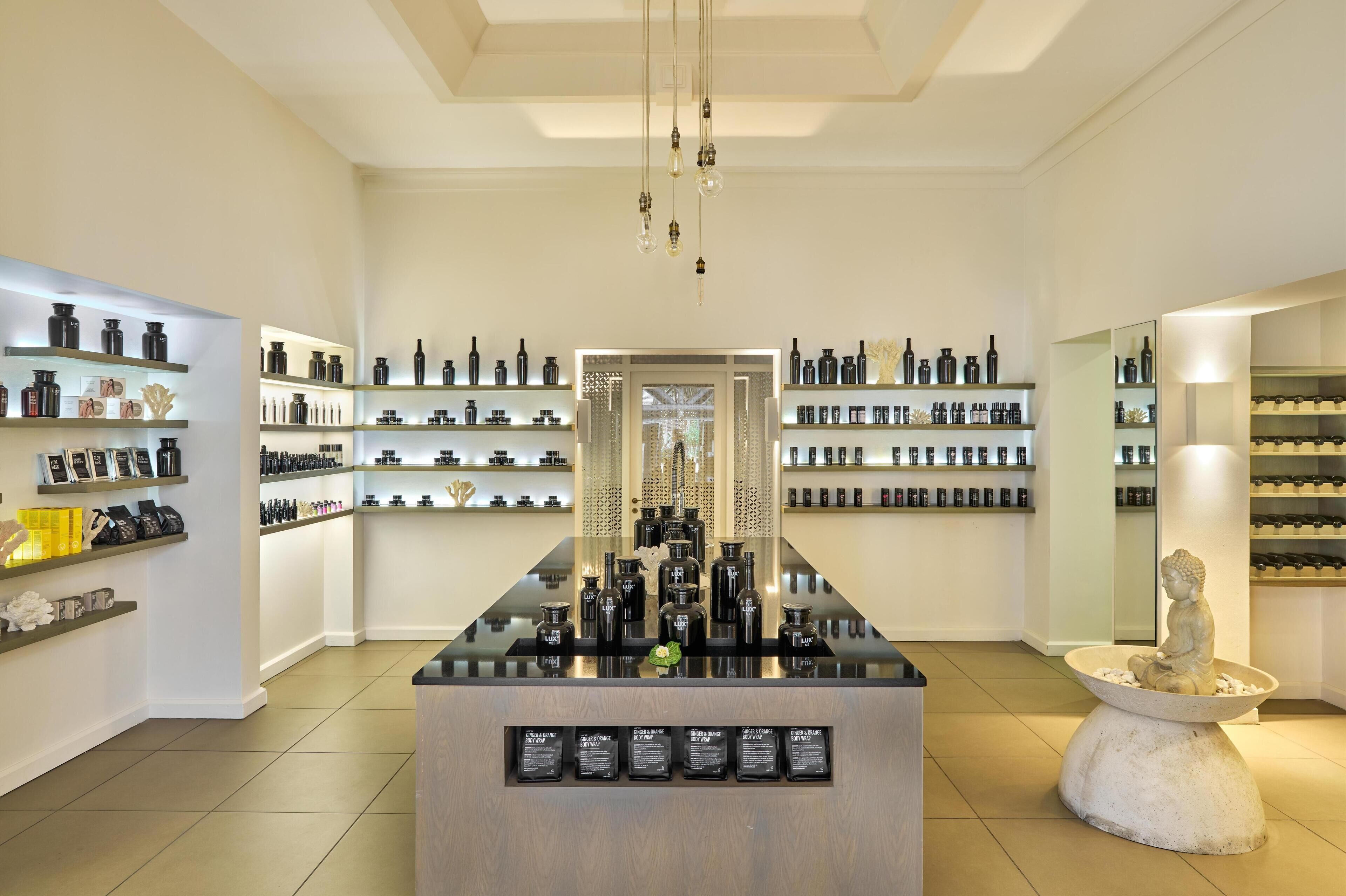 A modern retail space with shelves of products, a central display table, and a statue.