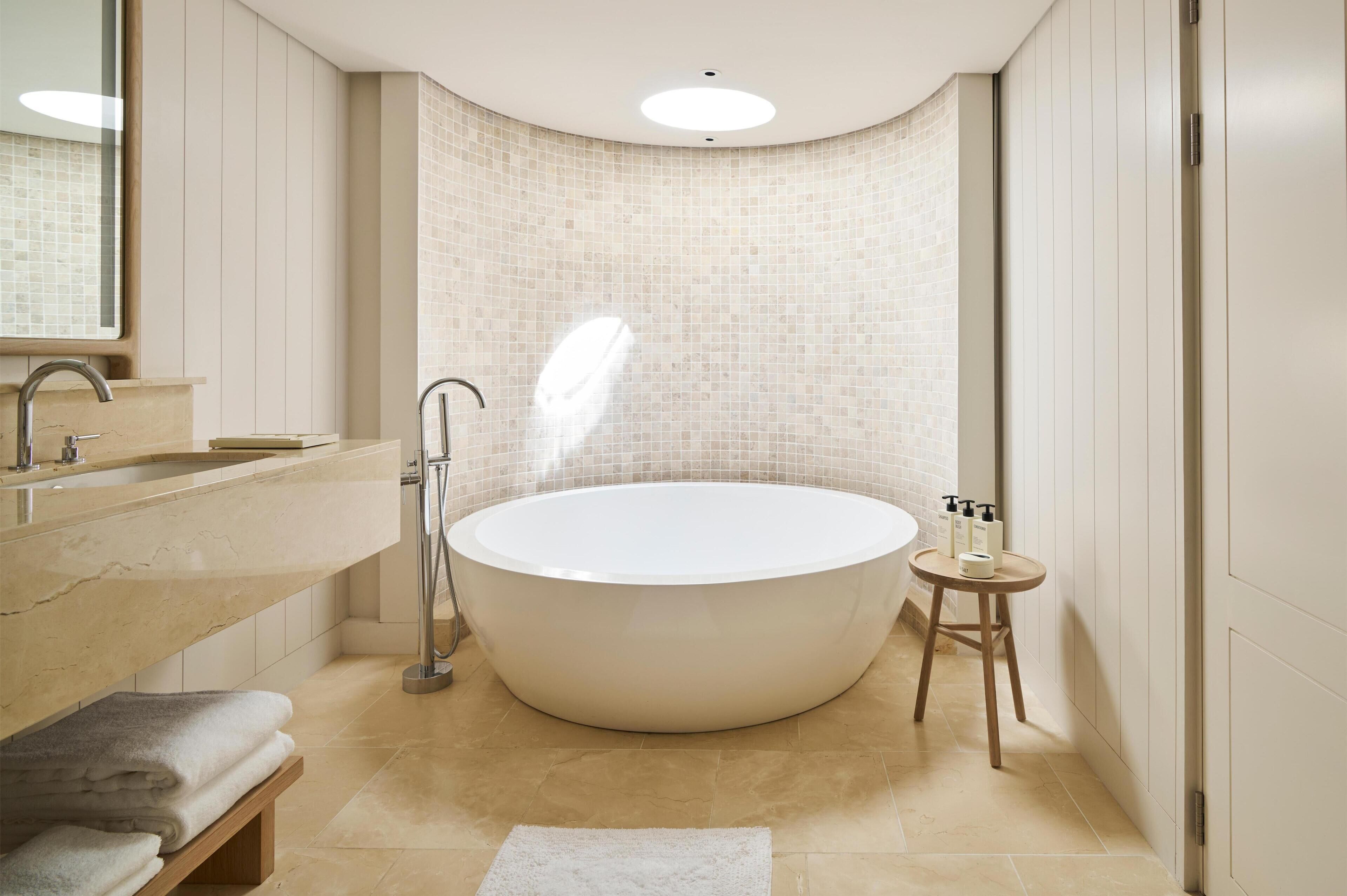 Ein modernes Badezimmer mit einer freistehenden Badewanne, einem Waschtisch und einem Spiegel.