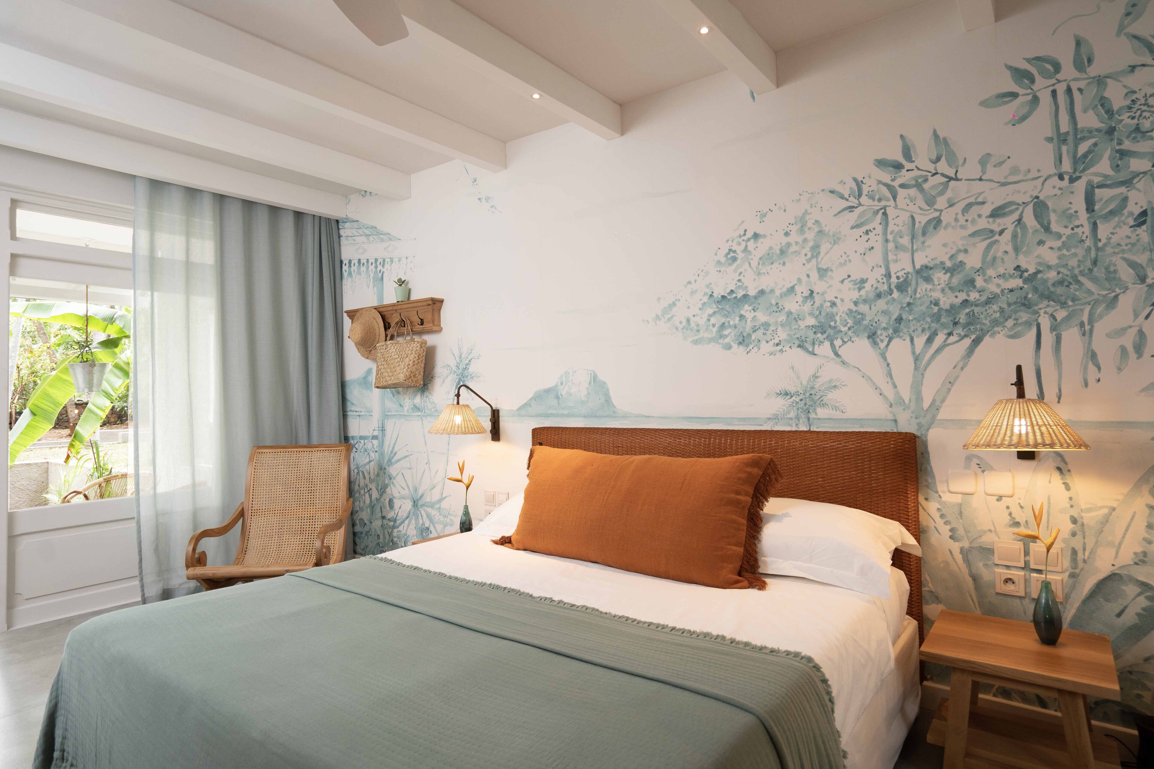 A bedroom with a large bed, a chair, a nightstand, and a wall mural.