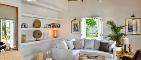A modern living room with a white sofa, wooden coffee table, and wicker chairs.