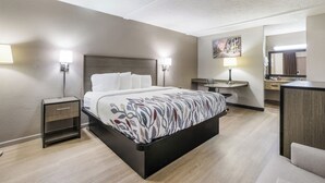 Une chambre d’hôtel avec un lit, des tables de chevet, un bureau, une chaise, un miroir et un tableau au mur.