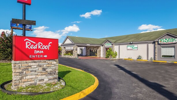 Un hôtel Red Roof Inn avec un ciel dégagé, une entrée en pierre et un parking.