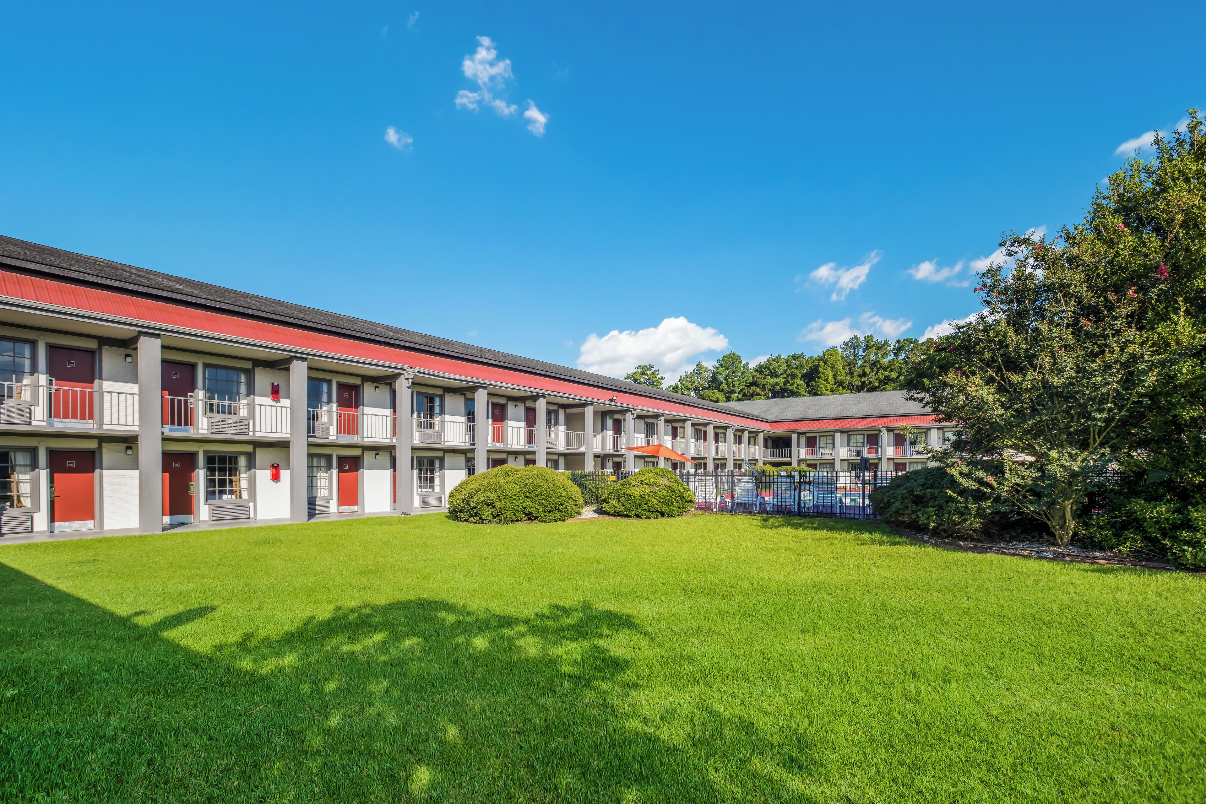 Un motel avec un toit rouge, de nombreux balcons et une pelouse bien entretenue.