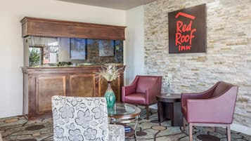 Un hall d’entrée de Red Roof Inn avec un mur en pierre, un bar en bois et un espace salon.