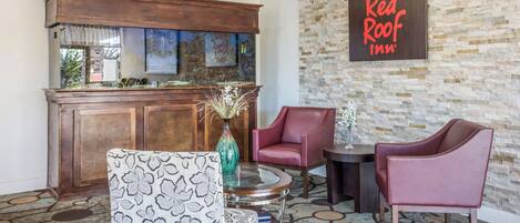 A Red Roof Inn lobby with a stone wall, wooden bar, and seating area.