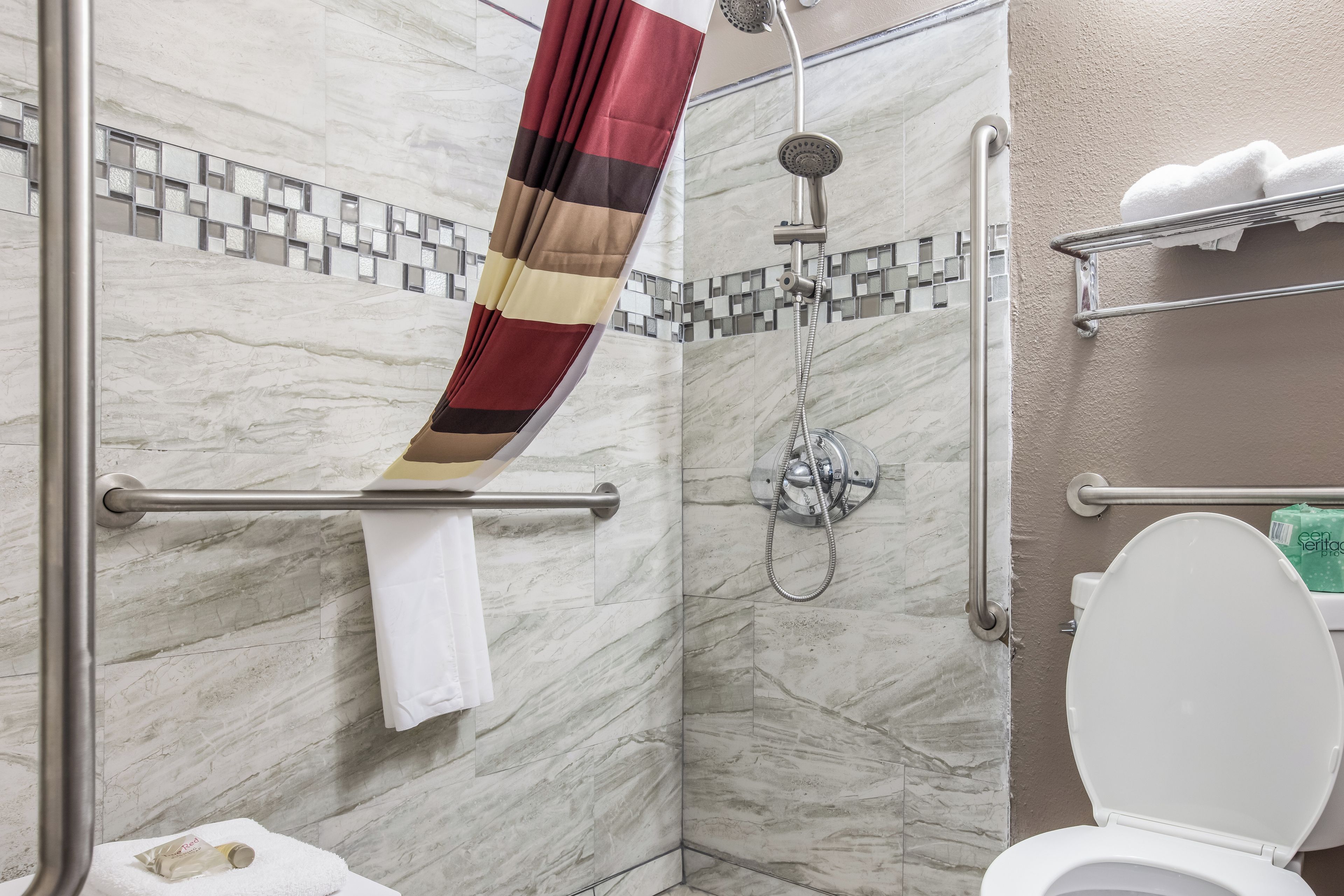A bathroom with a shower, toilet, and a towel rack.