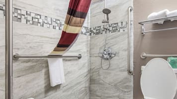 A bathroom with a shower, toilet, and a towel rack.