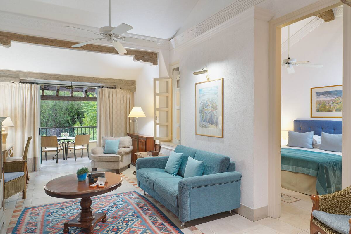 A spacious living room with a blue sofa, a coffee table, and a dining area with chairs and a table.