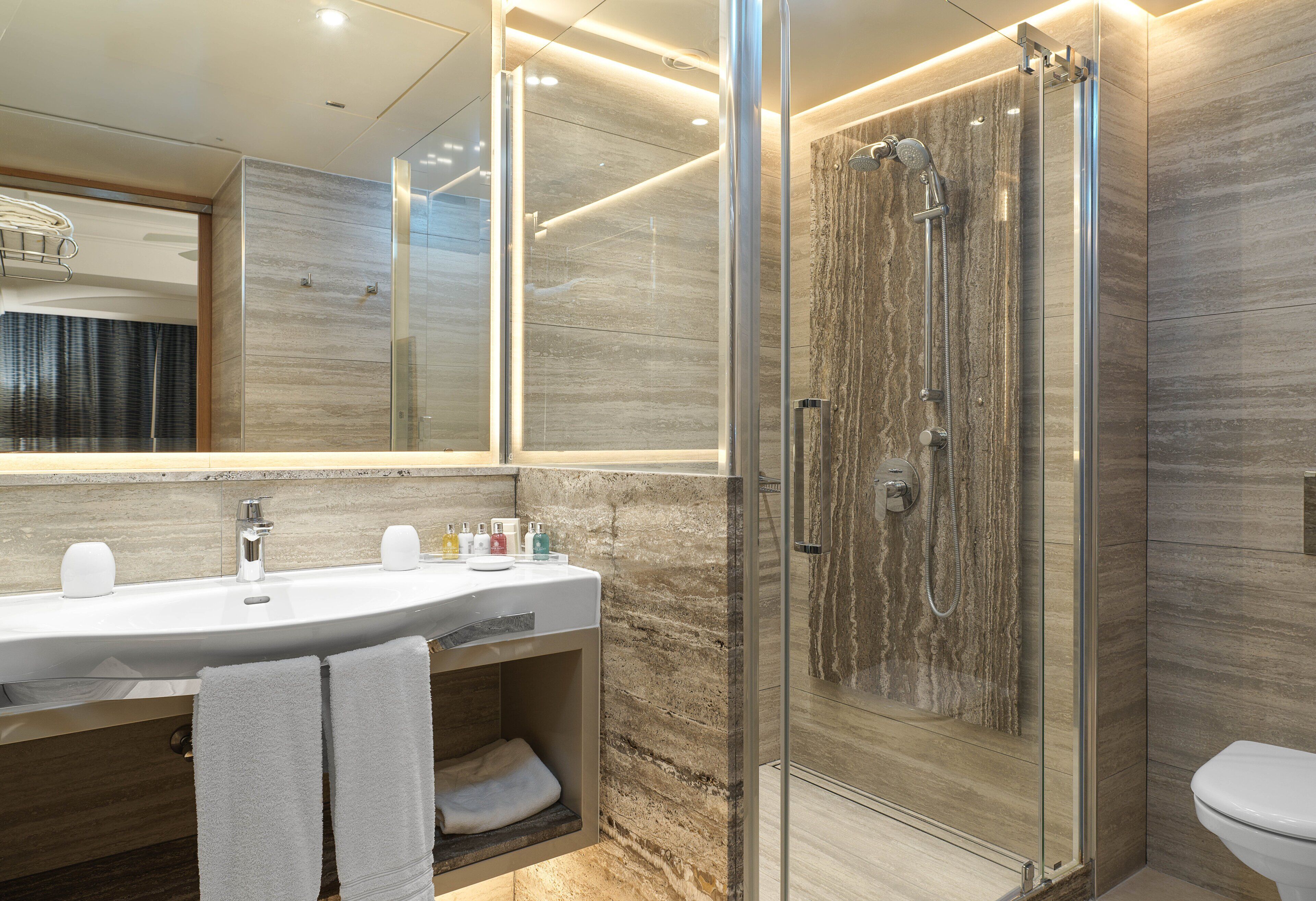 A modern bathroom with a glass-enclosed shower, a vanity with a sink, and a toilet.