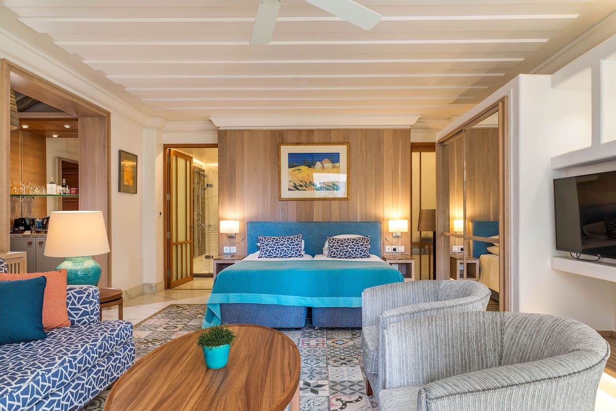 A hotel room with a large bed, a sofa, a coffee table, and a TV.