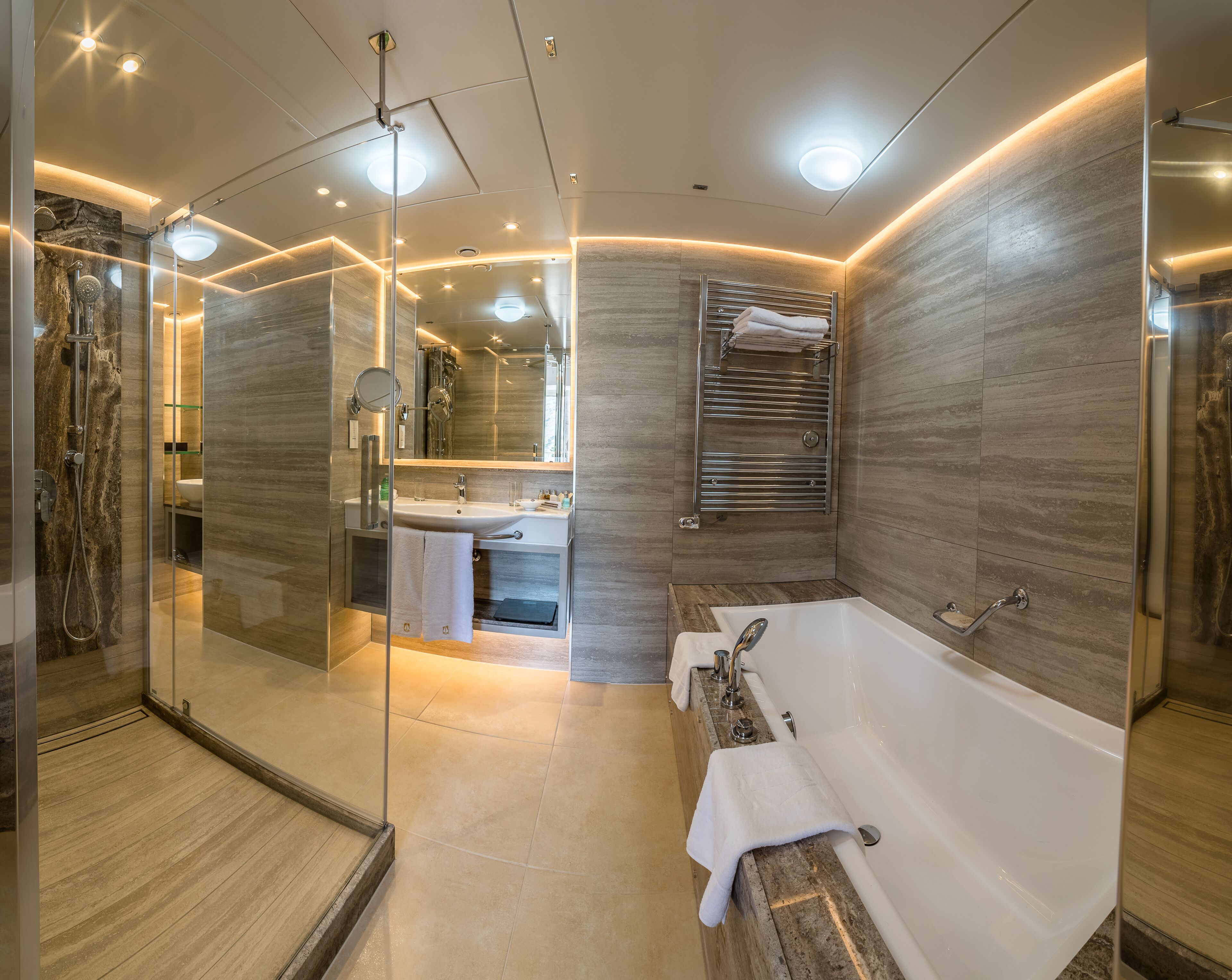 A modern bathroom with a glass-enclosed shower, a large bathtub, and a vanity with a mirror.
