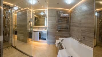 A modern bathroom with a glass-enclosed shower, a large bathtub, and a vanity with a mirror.