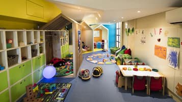 A children's playroom with colorful toys, a play mat, and a table with chairs.