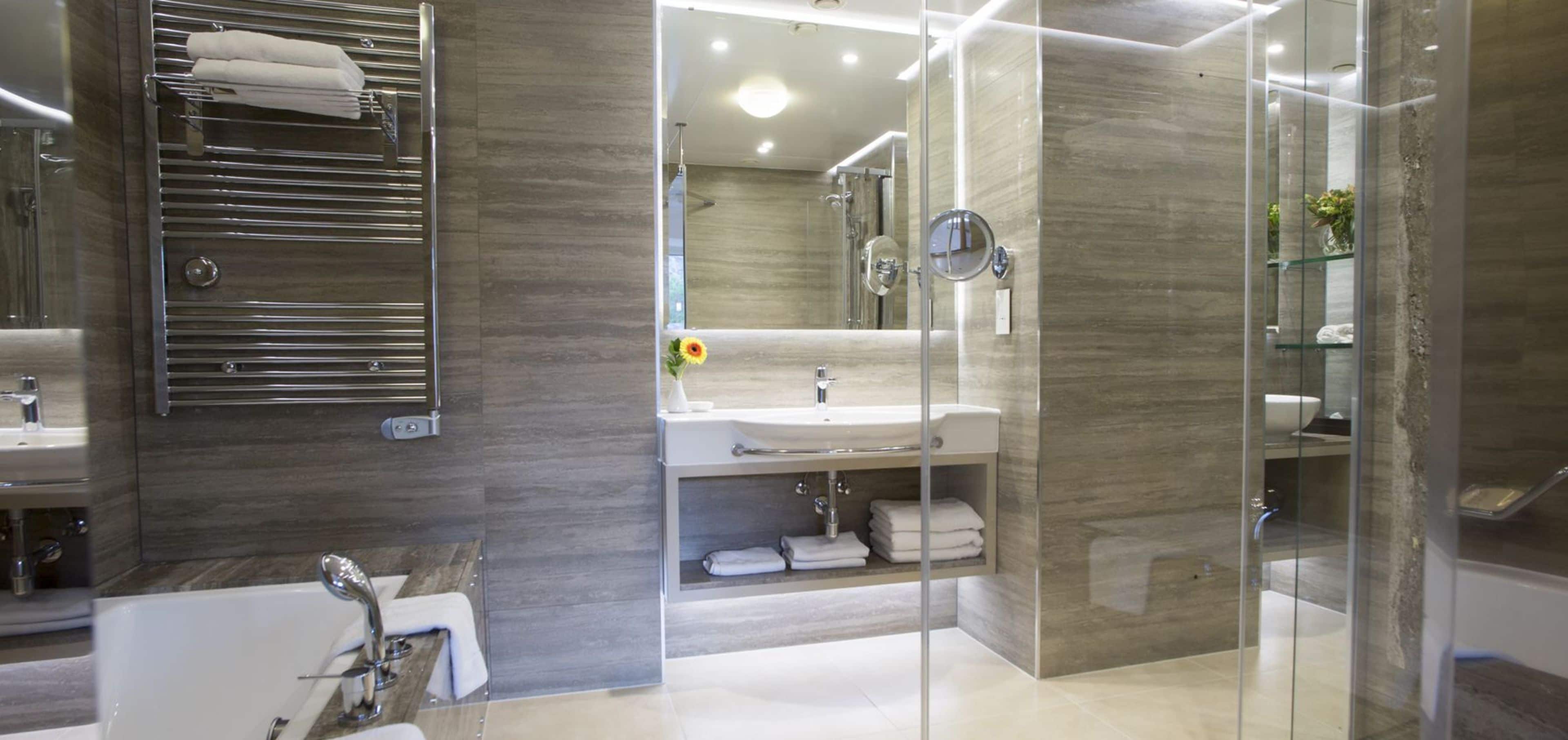 A modern bathroom with a glass-enclosed shower, a large mirror, and a vanity with a sink.