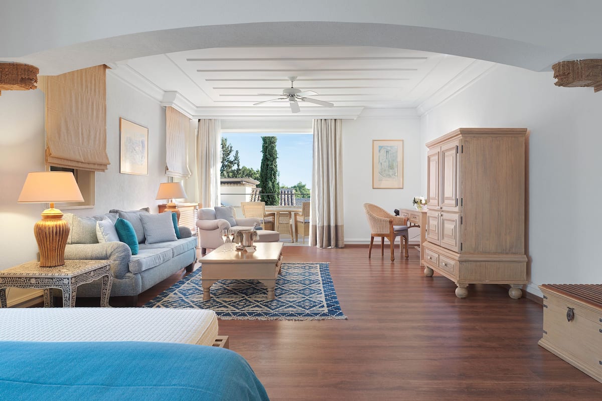 A spacious room with a bed, a sofa, a dining table, and a cabinet.