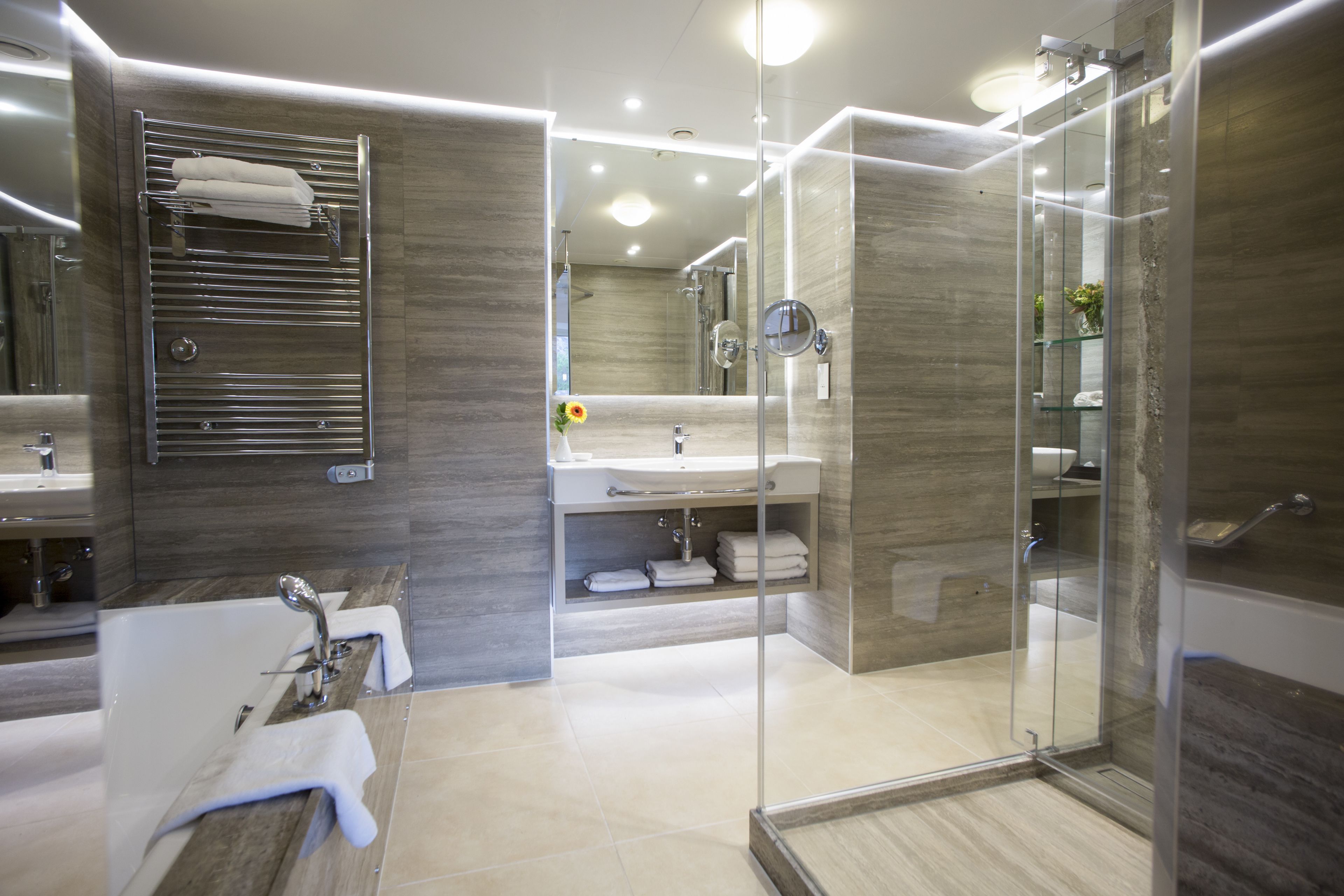 A modern bathroom with a glass-enclosed shower, a freestanding bathtub, and a vanity with a mirror.