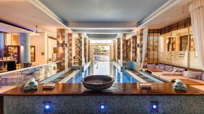 A modern hotel lobby with a central pool, seating areas, and a reception desk. - Columbia Beach Resort (Pissouri)