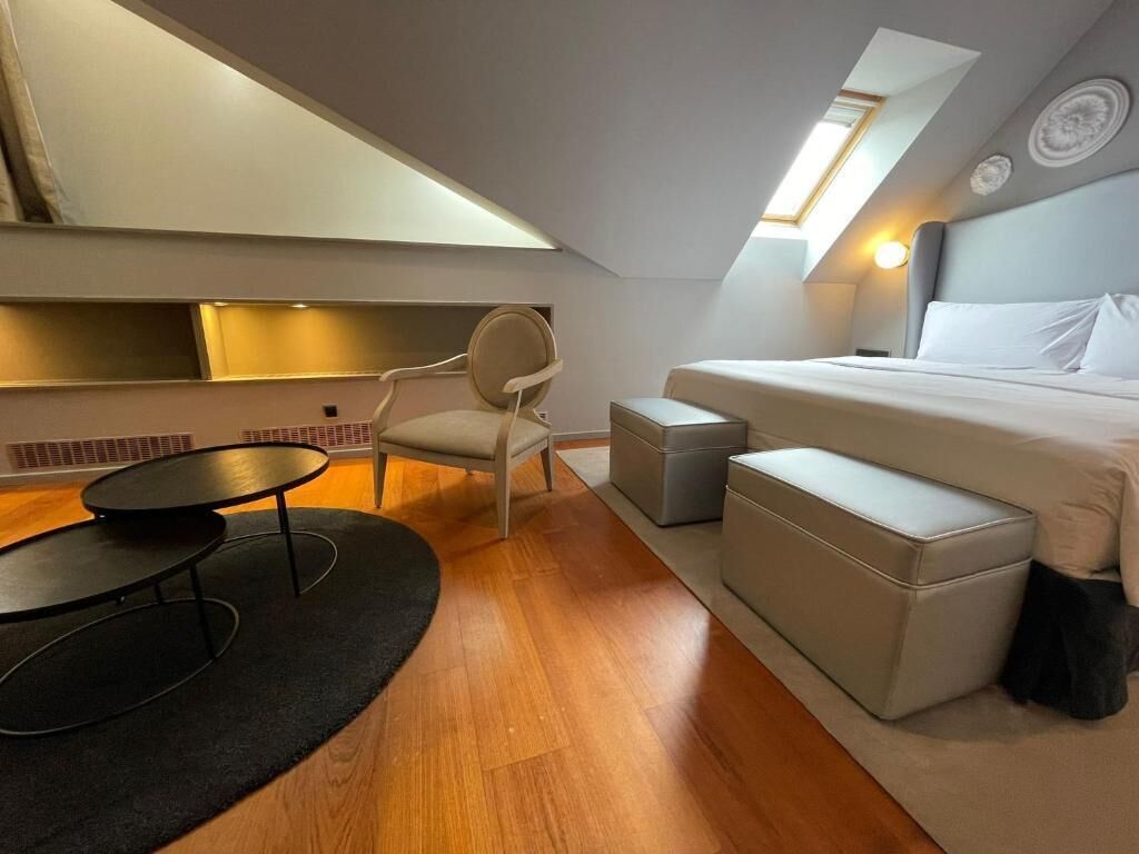 A compact, modern room with a bed, a chair, a small table, and a sofa.