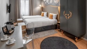 Une chambre d’hôtel moderne équipée de deux lits, d’un bureau avec une machine à café et d’un téléviseur fixé au mur.