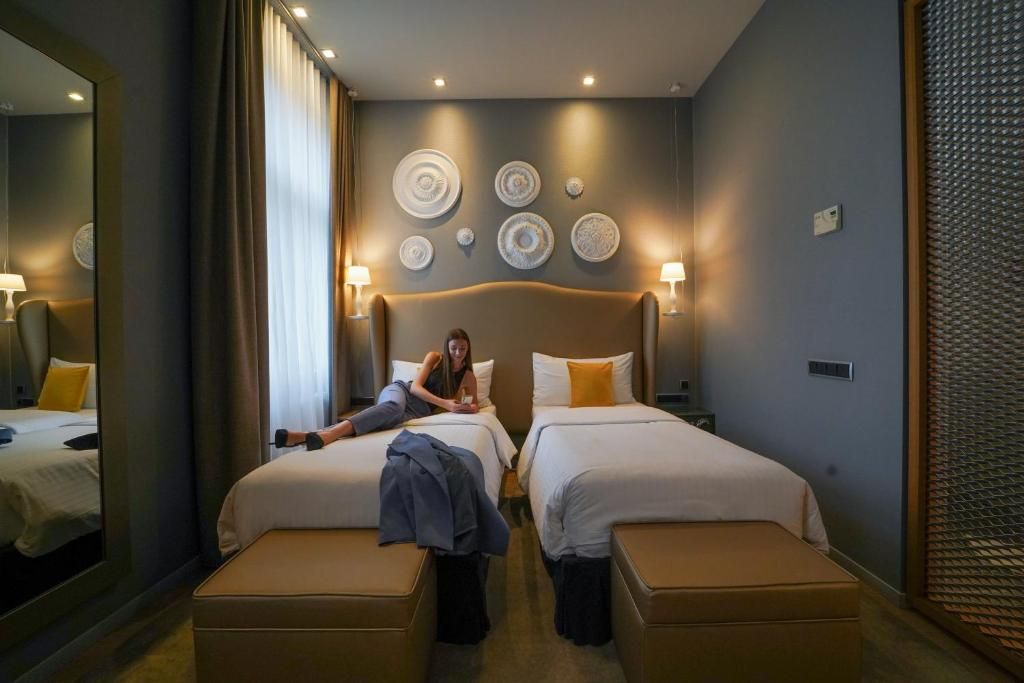 A hotel room with two beds, a large mirror, and decorative wall plates.