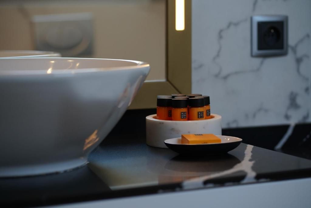 A kitchen counter with a large white bowl, a small white container with orange items, and a black plate with a yellow object.