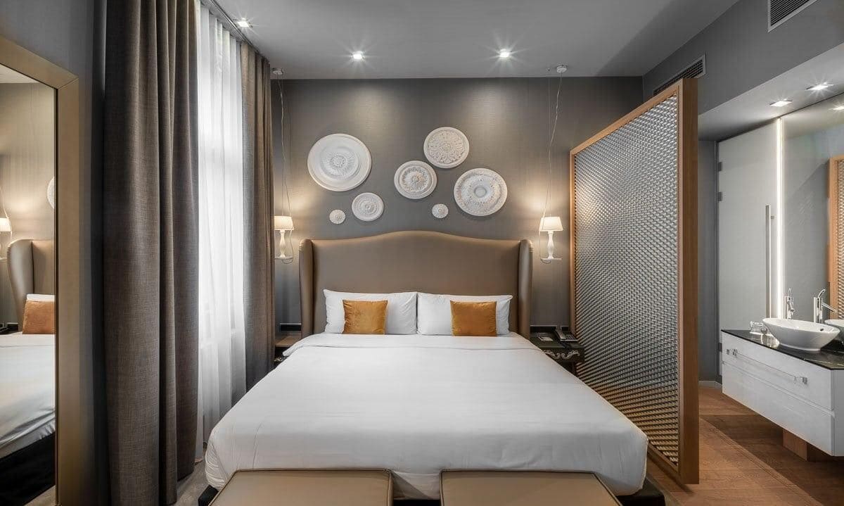 A modern bedroom with a large bed, bedside lamps, a headboard, and wall decor.