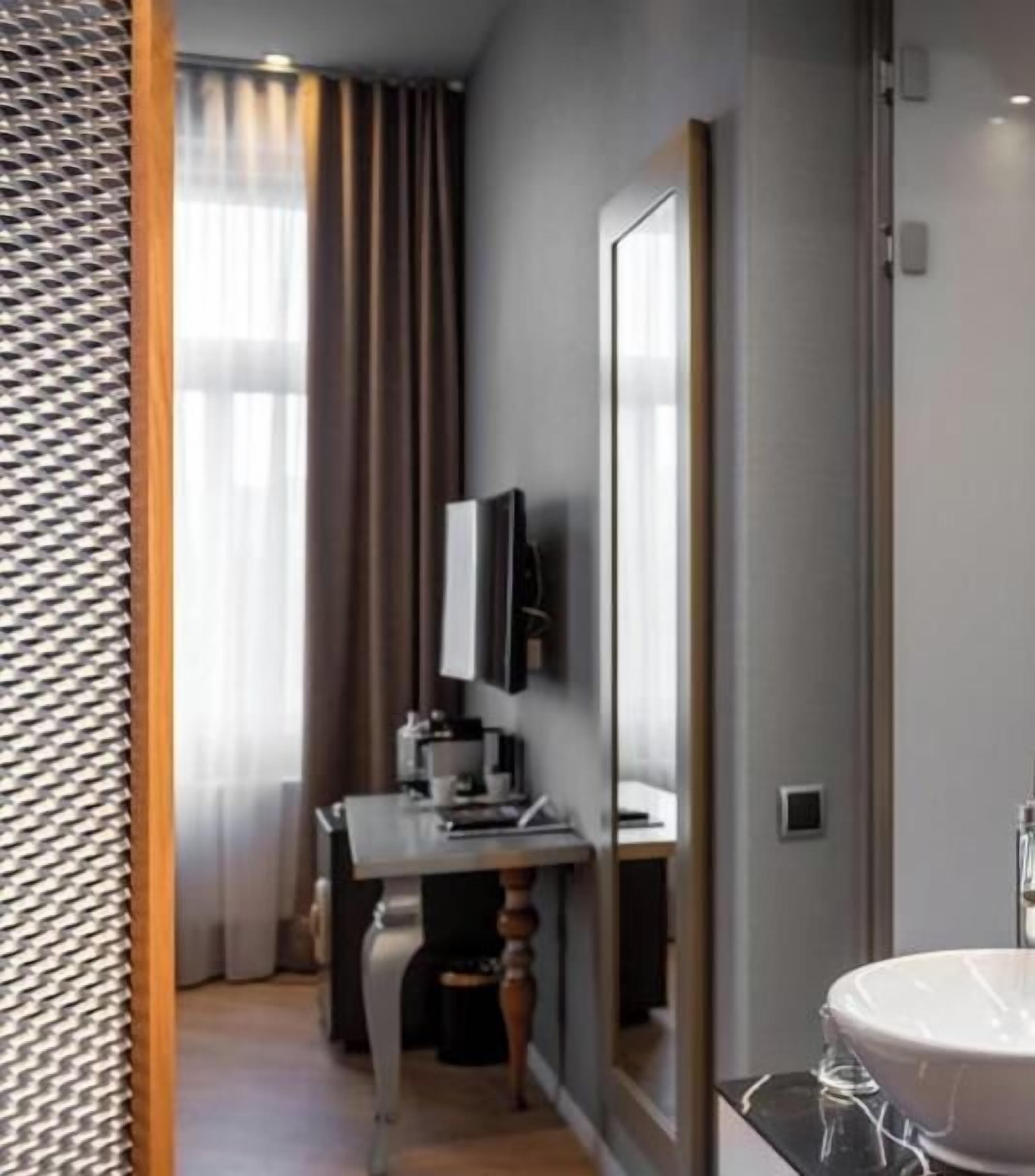 Une salle de bain moderne avec un grand miroir, un lavabo et un téléviseur fixé au mur.