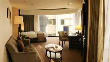 A hotel room with a bed, a sofa, a desk, and a coffee table.