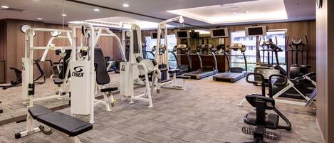 Un gimnasio con diferentes equipos de ejercicio, como cintas de correr, elípticas y máquinas de pesas.