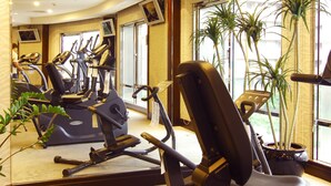 A gym with exercise equipment, large windows, and indoor plants. - Grand Forward Hotel (New Taipei City)