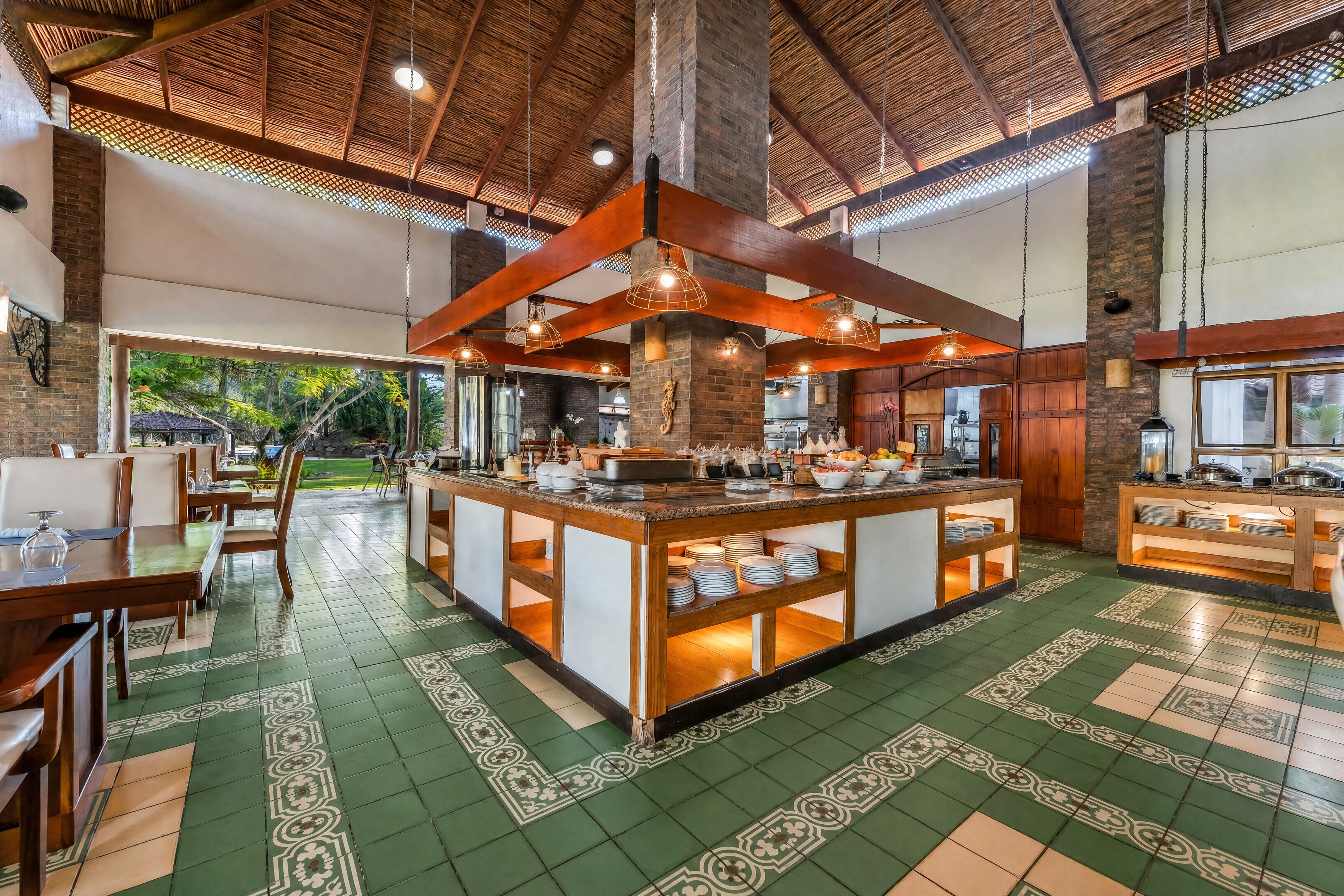 Un vaste espace dédié à la salle à manger, doté d’un îlot central, de poutres en bois et de carreaux de sol décorés.